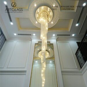 Hình ảnh thực tế đèn thông tầng pha lê Artglass Rosamunde Spiral CE lắp đặt tại sảnh, với dải pha lê cao cấp xoắn ốc dài 3.2m trên nền khung đồng mạ vàng.